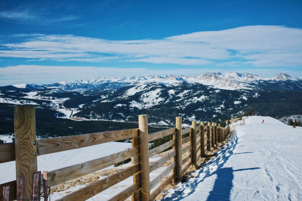 campo di neve e recinzione di legno marrone vicino alla montagna di giorno